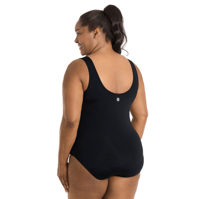 Plus size woman, facing back, wearing JunoActive plus size QuikEnergy Color Block Tank Suit in Turquoise and black color blocking. The back is all black with a scoop line back.