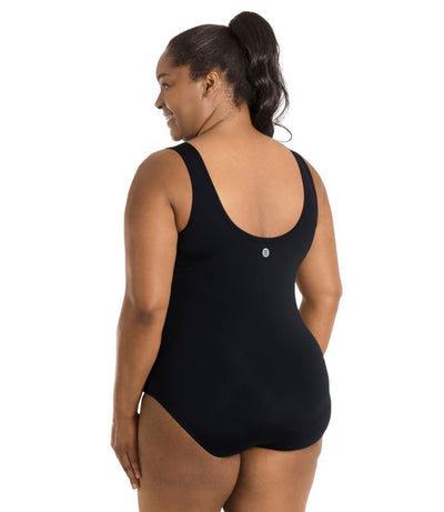 Plus size woman, back view, wearing JunoActive plus size QuikEnergy Spa Suit Black.  The back of the suit is solid black with a scoop neckline.