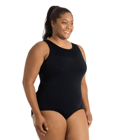 Plus size woman, side view, wearing JunoActive plus size QuikEnergy Spa Suit Black. The suit is solid black, has a scoop neckline and conservative leg opening.