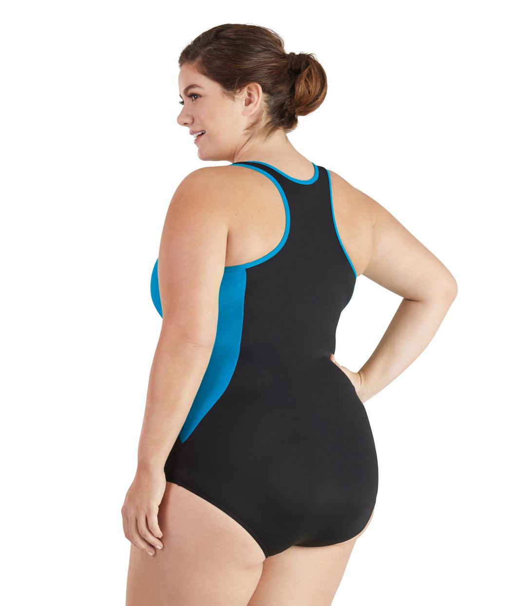 Plus size woman, back view with hand on hip, wearing JunoActive plus size QuikEnergy Zip Tank Suit Turq and Black. Neck binding, armhole binding, and princess seam blocking is turquoise. The main body of the suit is solid black, has a racerback and conservative leg opening.