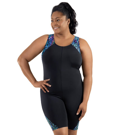 Plus-size model wearing JunoActive's QuikEnergy Aquatard in coral reef print. She is facing forward with one hand on her hip and other by her side.