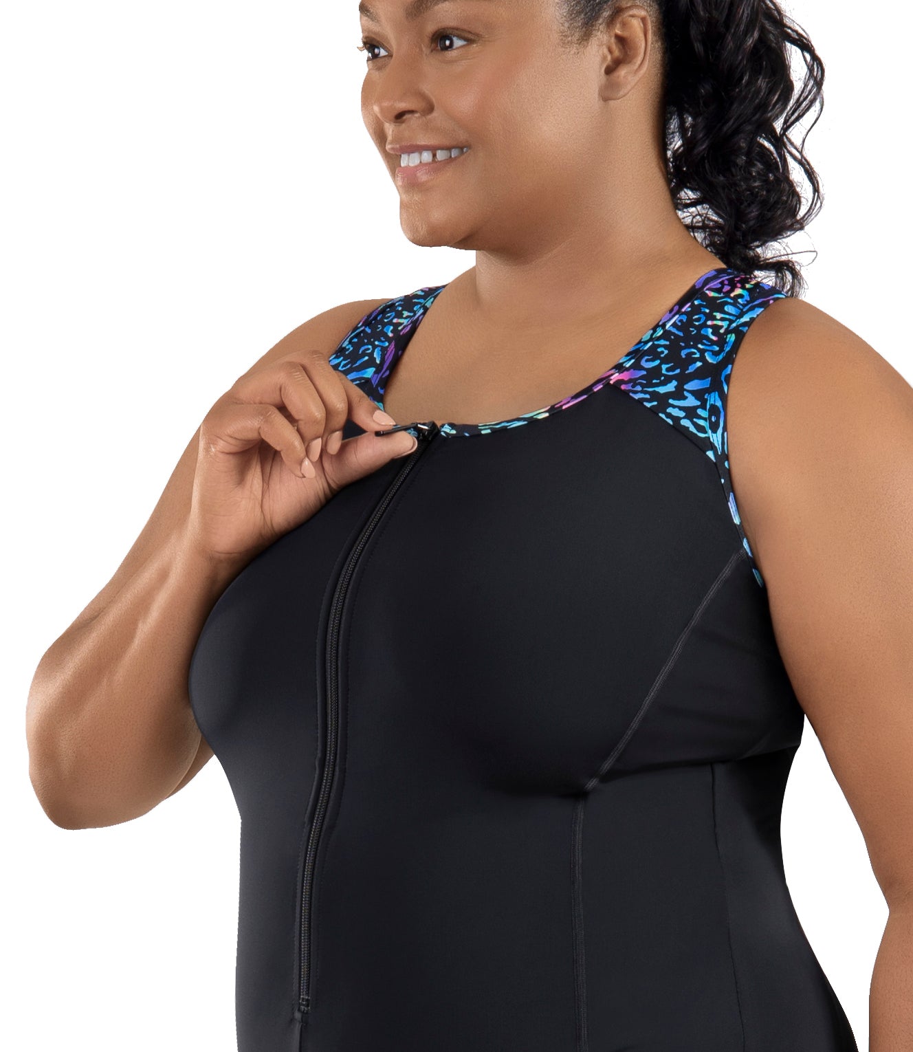 Plus-Size Model, facing forward side view, wearing JunoActive's QuikEnergy Racerback Zip Front Aquatard in color reef print. Right hand holding zipper at top of suit.