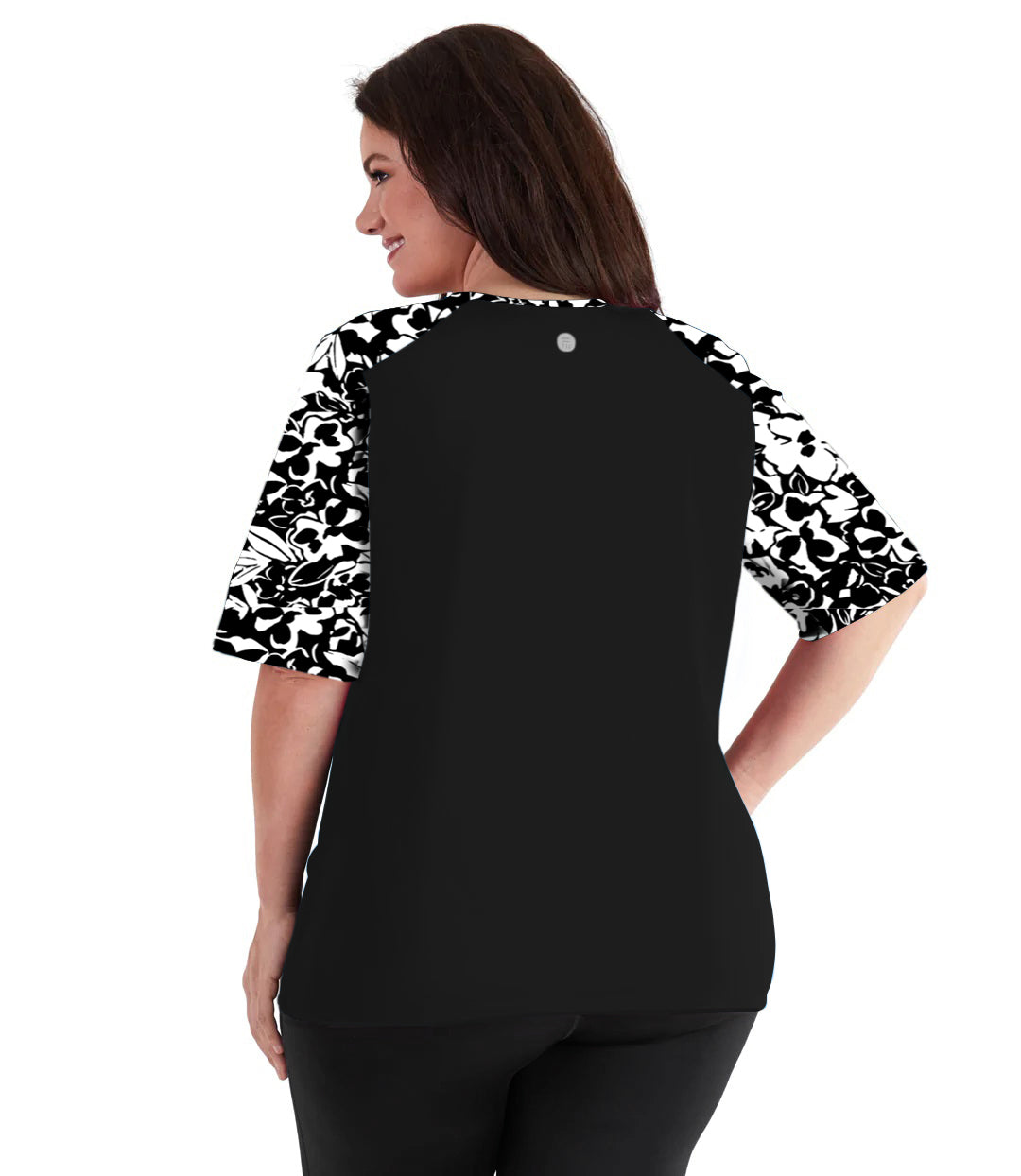 Plus size woman, facing back wearing JunoActive QuikEnergy Lite Swim and Beach short Sleeve Top Hibiscus Black. Solid Black on the center  and Hibiscus print on the sleeves and upper shoulders. The short sleeves end at the elbow.