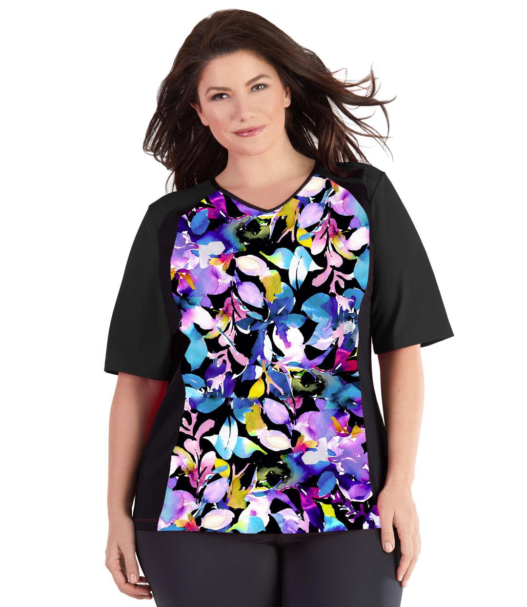 Plus size woman, facing front, wearing QuikEnergy Short Sleeve Swim and Sun Top South Pacific Black. Multicolor floral on the torso and solid black colorblocking on the sleeves and waist. Long cover short sleeves meeting at the elbow. 