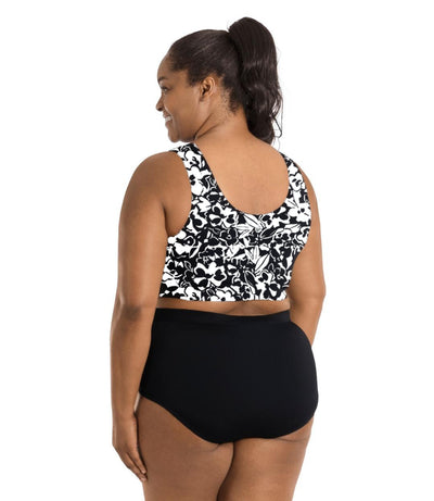 Plus size woman, facing back with face at profile, wearing JunoActive's QuickEnergy Swim Bra is Hibiscus print. Her arms fall naturally to her side and she's wearing JunoActive's swim briefs in black.