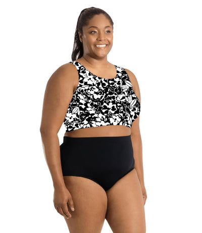 Plus size woman, facing side, wearing JunoActive's QuickEnergy Swim Bra is Hibiscus print. Her arms fall naturally to her side and she's wearing JunoActive's swim briefs in black.