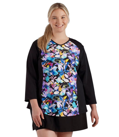 Plus size woman, facing front, wearing QuikEnergy  ¾ Sleeve Swim and Sun Top South Pacific Black. Multicolor floral print on the center torso and solid black colorblocking on the sleeves and waist .