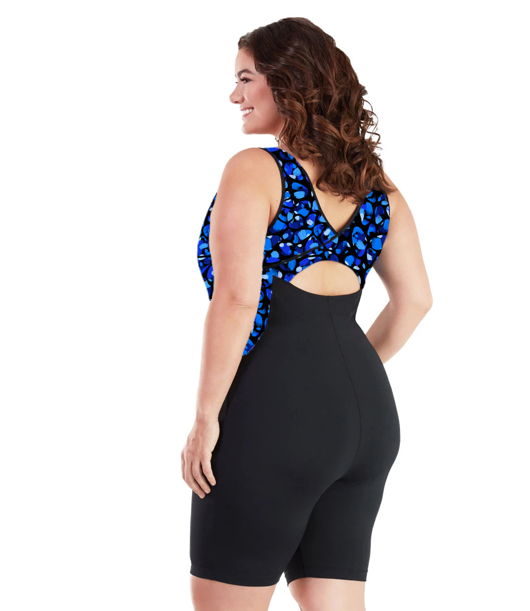 Plus size woman, back view, wearing JunoActive plus size AquaSport Crossback Aquatard Ocean Blues Print Black. The overlapping crossback and side blocking detail of the tanksuit is a multi colored blue bubble print. The main body of the suit is solid black, keyhole opening at the mid-back. The leg hits a few inches above the knee.