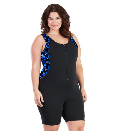 Plus size woman, facing front, wearing JunoActive plus size AquaSport Crossback Aquatard Ocean Blues Print Black. Front princess seam blocking is a multi colored blue bubble print.  The main body of the suit is solid black, has a black zipper in front with black bindind and the neck and armholes. The leg hits a few inches above the knee.