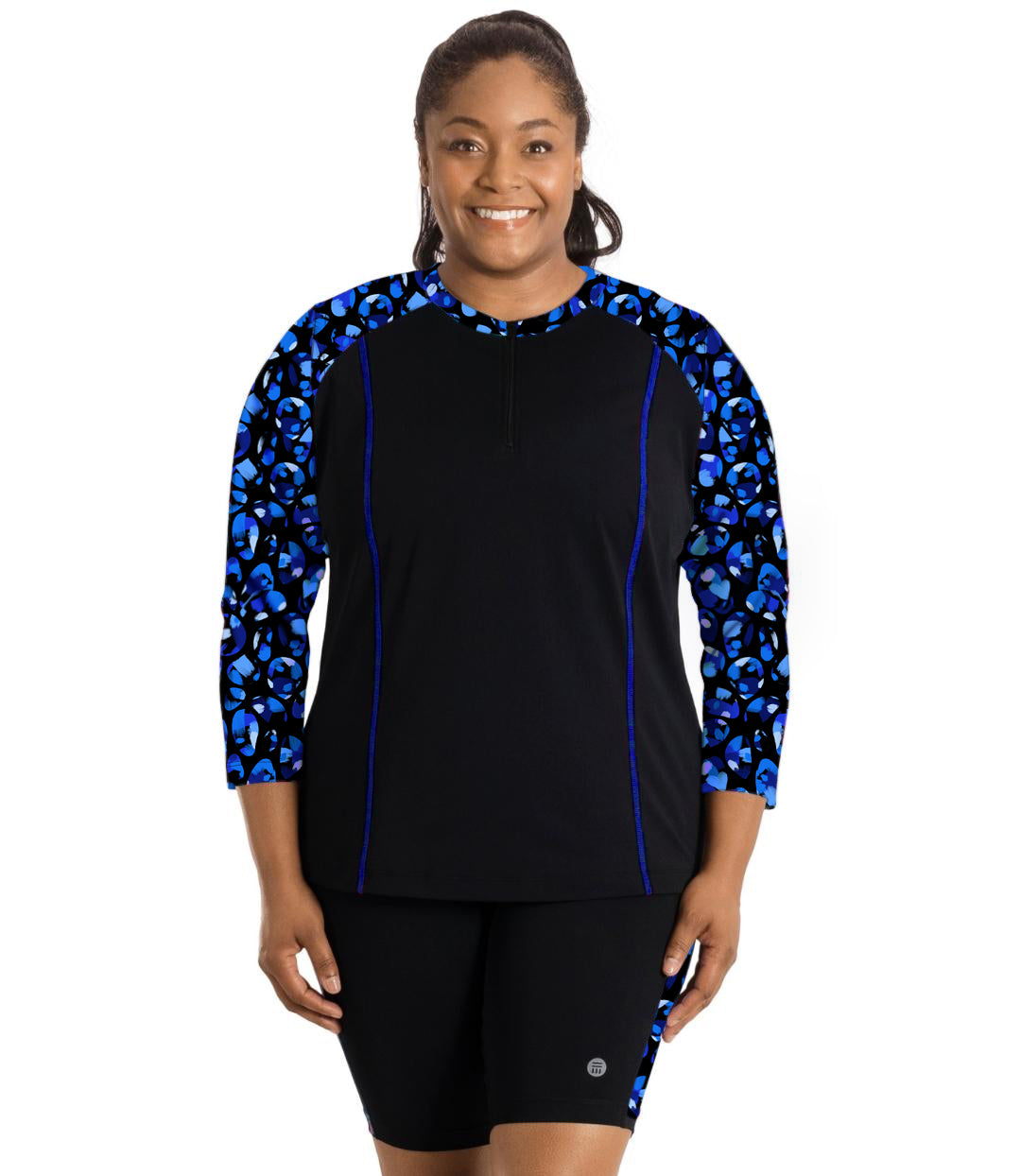 Plus size woman, facing front, wearing AquaSport Long Sleeve Rash Guard Ocean Blues Print Black. Colorblock accent on the waist and shoulders in a blue bubble print. 7/8 sleeve length with princess seaming down the front.   