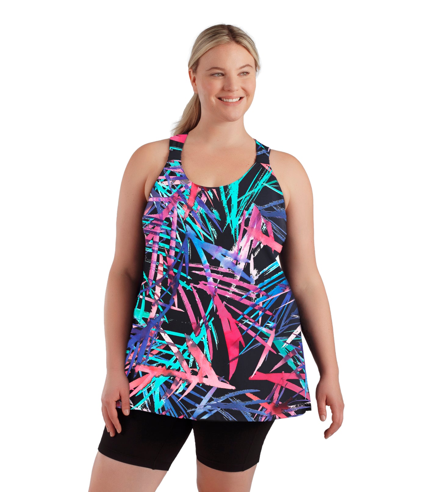 Plus size woman, facing front, wearing JunoActive plus size AquaSport Hanalei Tankini Top Sunset Palm Print. Shoulder cinch detail in front and vents at the side seams. Pink, blue and teal abstract line print.   