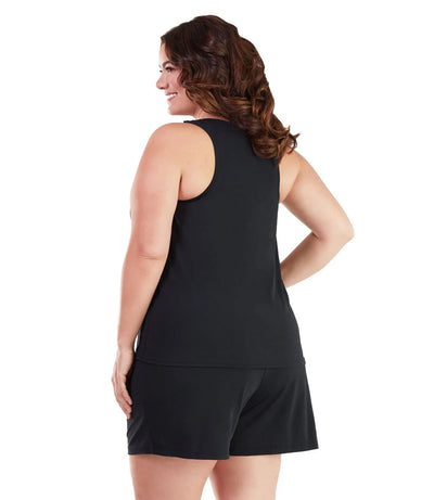 Plus size woman, facing back view, wearing AquaSport Tankini Top Sunset Palm Print Black. The back of the tankini is razor back and solid black falling mid-bottom. 