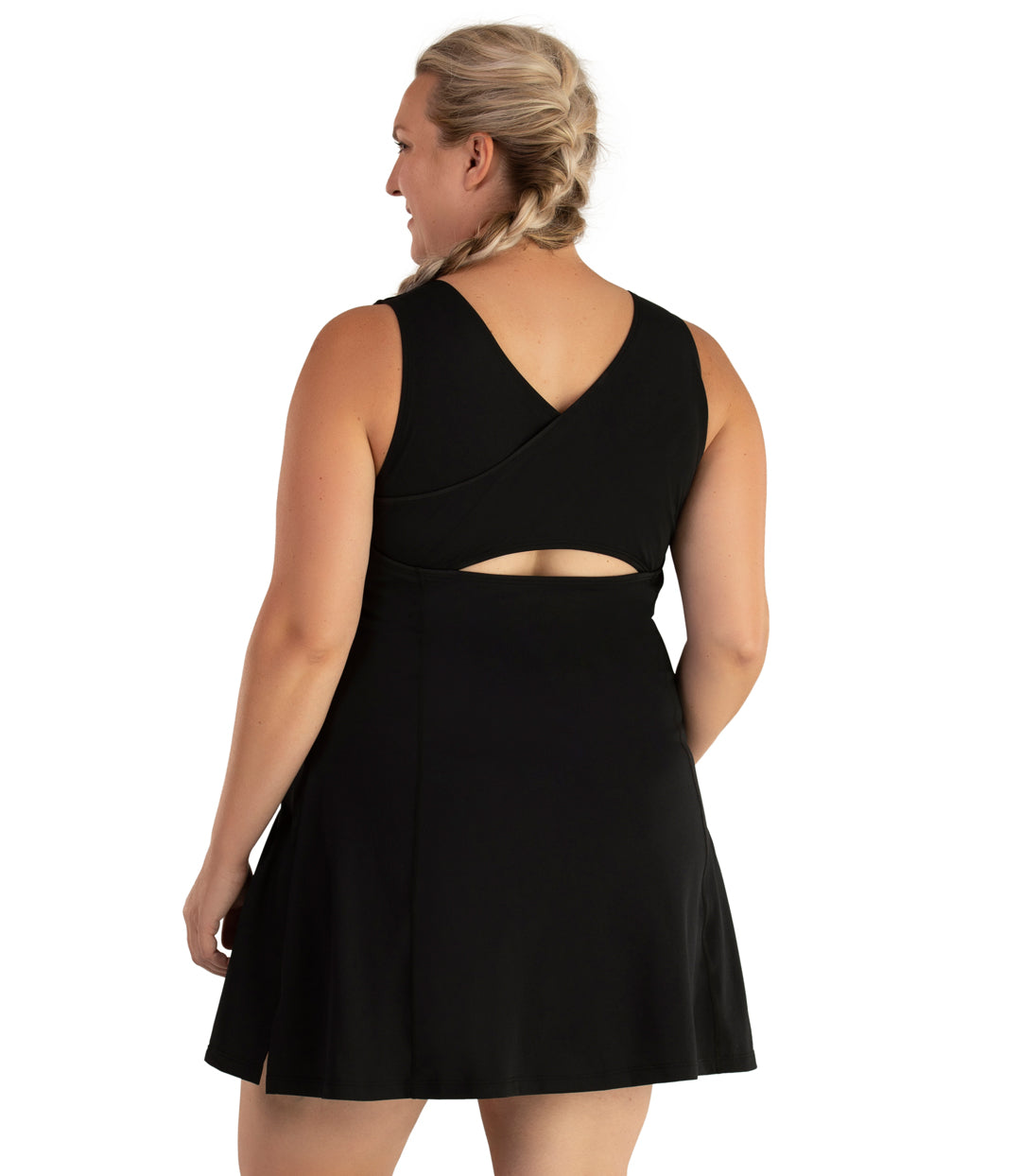 Plus size woman, back view, wearing JunoActive plus size AquaSport Crossback Swim Dress Pacific Blue Black. The back of the swim dress is black with an overlapping crossback detail. The dress has a keyhole at mid back, slight a-line shape and ends mid-thigh.