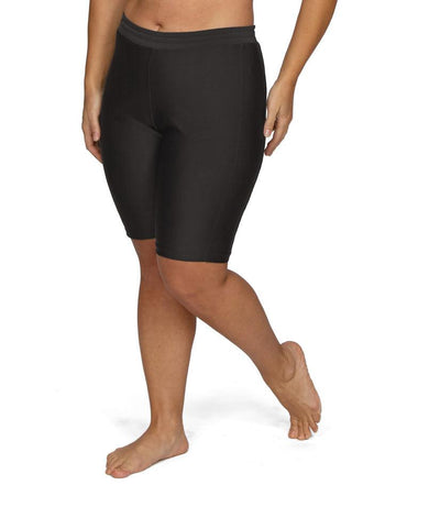 Plus size woman, facing front, wearing AquaSport Long Fitted Swim Shorts in black. Length hitting right above the knee. Fitted in the thigh.