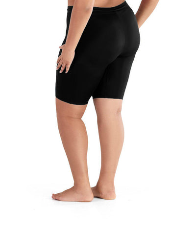 Plus size woman, back view, wearing AquaSport Long Fitted Swim Shorts in black. Length hitting right above the knee. Fitted in the thigh.