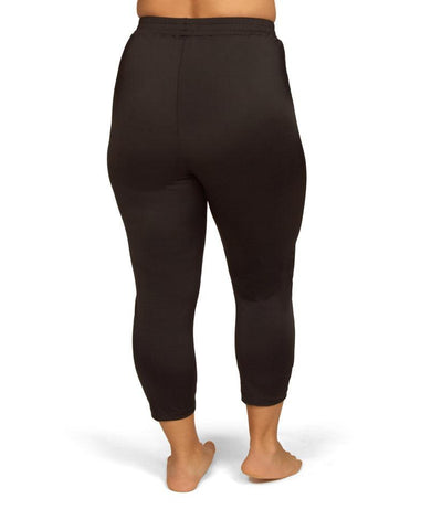 Plus size model, back view, wearing AquaSport Swim Capris in solid black. Length hitting right above the ankle.