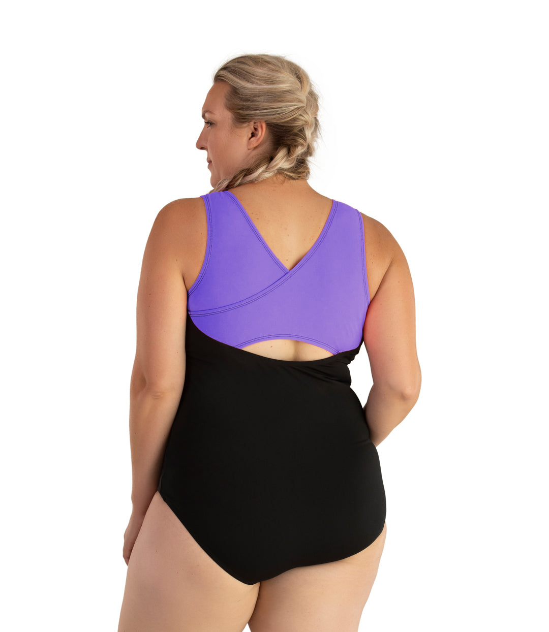 Plus size woman, back view, wearing JunoActive plus size AquaSport Crossback Tanksuit Purple Black. The crossback shoulder detail of the tanksuit is purple. The main body of the suit is solid black, keyhole opening at the mid-back.