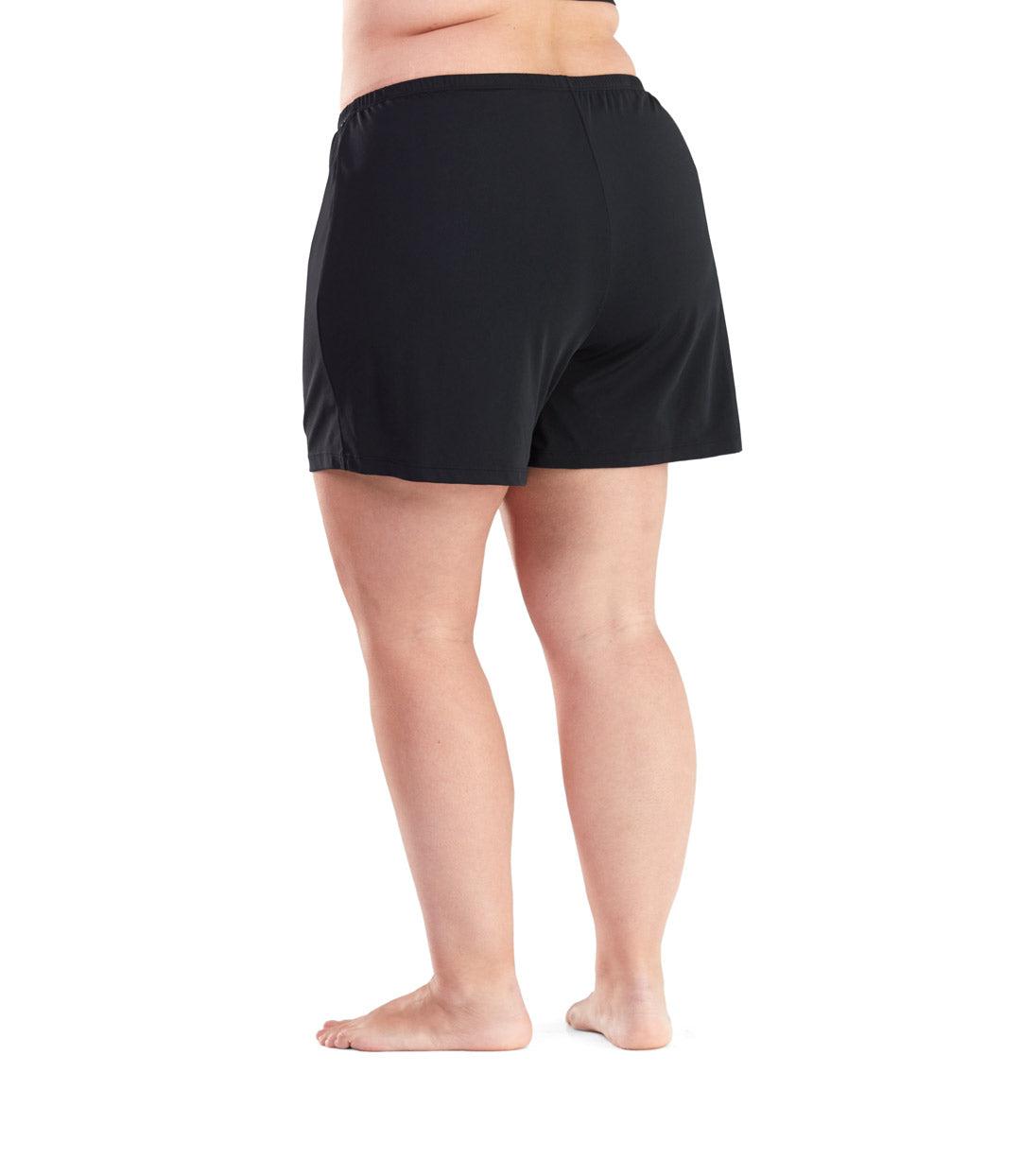 Plus size woman, back view, wearing AquaSport Swim Short with Brief in solid black. Loose leg opening landing mid-thigh.