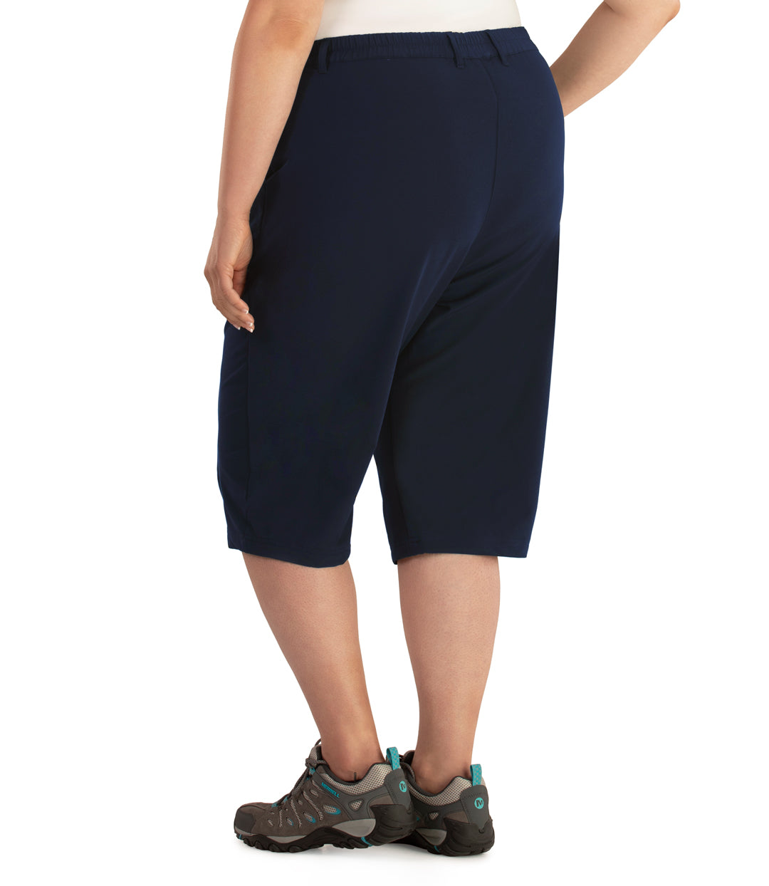 Bottom half of plus sized woman, back view, wearing JunoActive Hiking and Travel Short in color navy. Bottom hem is just below the knee. She is wearing hiking sneakers.