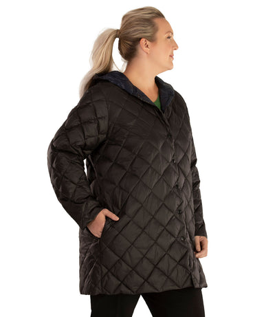 Plus size woman, front side view, facing right wearing a JunoActive plus size Quilted Light Weight Parka in black. The jacket has a hood, snap front closure and side zip pockets. Jacket quilting is a diamond pattern. The length of the plus size jacket hits below the hips.