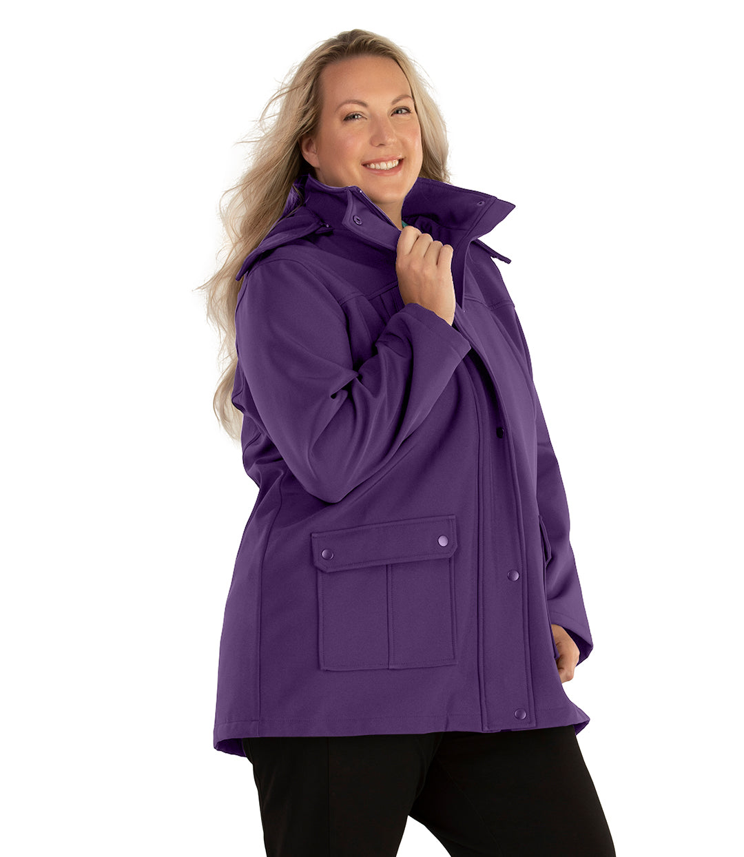 Plus size woman, side view facing right, wearing a JunoActive plus size Hooded Softshell Jacket in Amethyst Purple. The jacket has a removeable hood, zip front closure, zip chest pocket, and snap patch pockets at the hip. The length of the plus size jacket hits below the hips.
