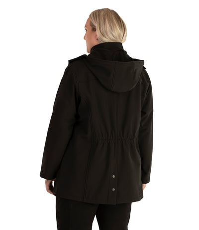 Plus size woman, back view with hood down, wearing a JunoActive plus size Hooded Softshell Jacket in Black. The jacket has a removeable hood, cinched waist, and snap vent at the center back hem. The length of the plus size jacket hits below the hips.