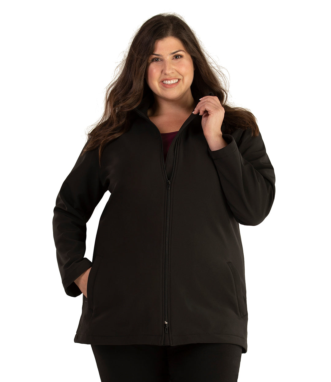Plus size woman, front view, wearing a JunoActive plus size Mock Neck Softshell Jacket in Black. The jacket has a mock neck collar, zip front closure and side pockets. The length of the plus size jacket hits just below the hips.