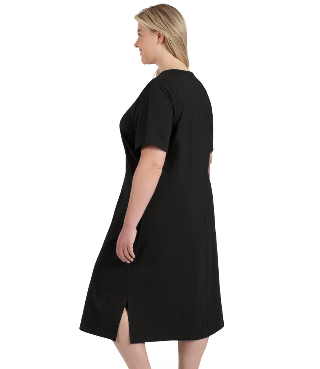 Plus size woman, facing back, wearing JunoActive’s Stretch Naturals Short Sleeve Dress in color black with her hands by her side. Slit in dress on side hem showing.