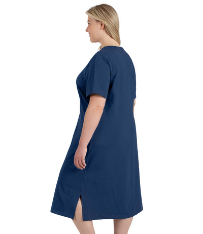 Plus size woman, facing to the back, wearing JunoActive plus size Stretch Naturals Short Sleeve Dress in the color french blue.
