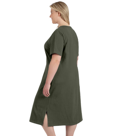 Plus size woman, facing to back left, wearing JunoActive plus size Stretch Naturals Short Sleeve Dress in the color moss green.