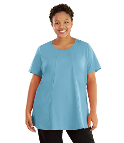 Plus size woman, facing front, wearing JunoActive plus size Stretch Naturals Lite Swing Top in the color Lake Blue. She is wearing JunoActive Plus Size Leggings in the color black.