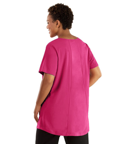 Plus size woman, facing front, wearing JunoActive plus size Stretch Naturals Lite Swing Top in the color Poppy Pink. She is wearing JunoActive Plus Size Leggings in the color black.