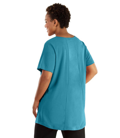 Plus size woman, facing front, wearing JunoActive plus size Stretch Naturals Lite Swing Top in the color Aquamarine. She is wearing JunoActive Plus Size Leggings in the color black. 