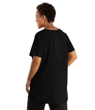 Plus size woman, facing front, wearing JunoActive plus size Stretch Naturals Lite Swing Top in the color Black Wild Print. The print is on the front of the shirt; the back of the shirt is solid Black. She is wearing JunoActive Plus Size Leggings in the color black. 