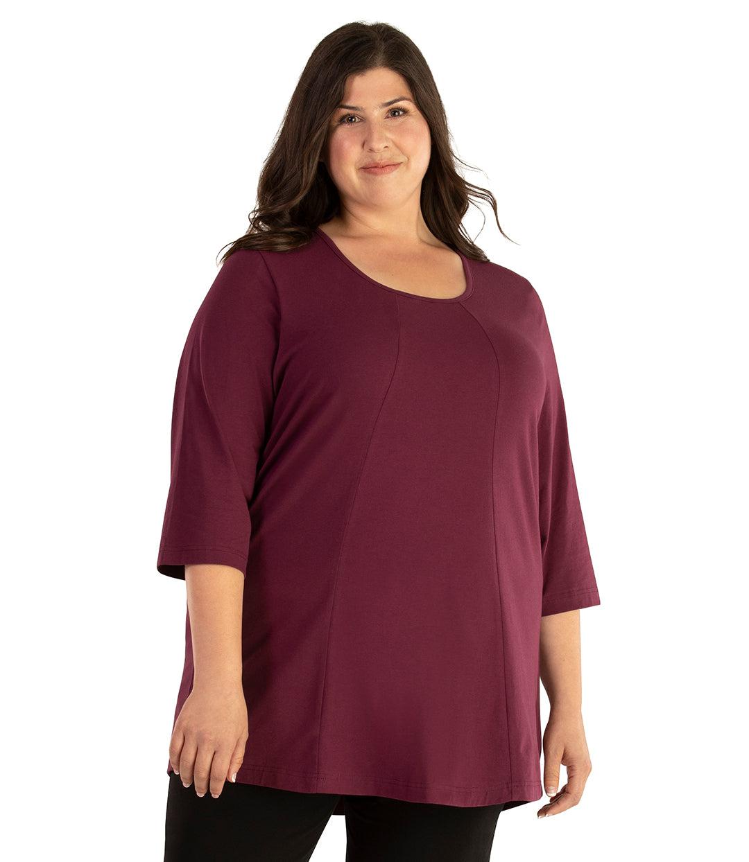 Plus size woman, facing front, wearing JunoActive plus size Stretch Naturals Lite ¾ Sleeve Swing Top in the color Dark Plum. She is wearing JunoActive Plus Size Leggings in the color Black. 