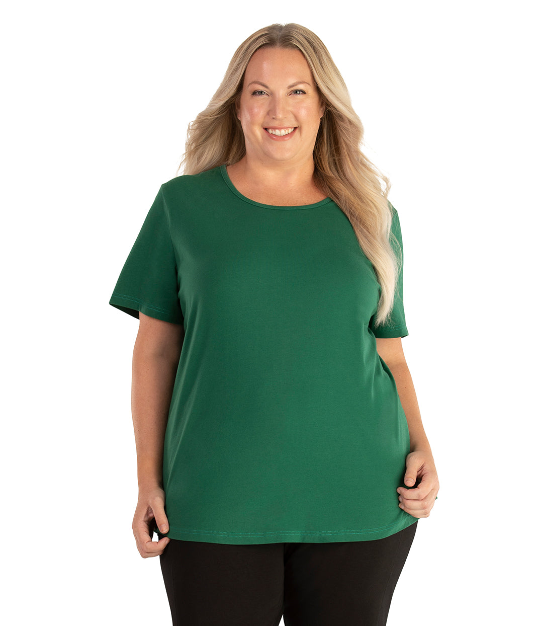 Plus size woman, facing front, wearing JunoActive plus size Stretch Naturals Lite Short Sleeve Scoop Neck Top in the color Forest Green. She is wearing JunoActive Plus Size Leggings in the color black. 