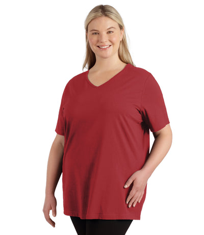 Plus size woman, facing front, wearing JunoActive plus size Stretch Naturals Lite Short Sleeve V-Neck Top in the color Rosy Red.  She is wearing JunoActive Plus Size Leggings in the color black. 