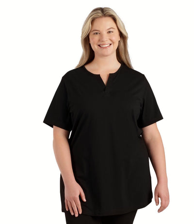 Plus size woman, facing front, wearing JunoActive plus size Stretch Naturals Lite Short Sleeve Split Collar Tunic in the color Black. She is wearing JunoActive Plus Size Leggings in the color black. 