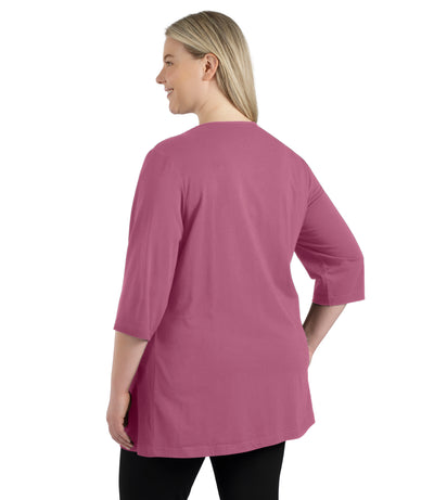Plus size woman, facing back, wearing JunoActive’s Stretch Naturals Lite 3/4 Sleeve V-neck Tunic, color mulberry. Arms by side.