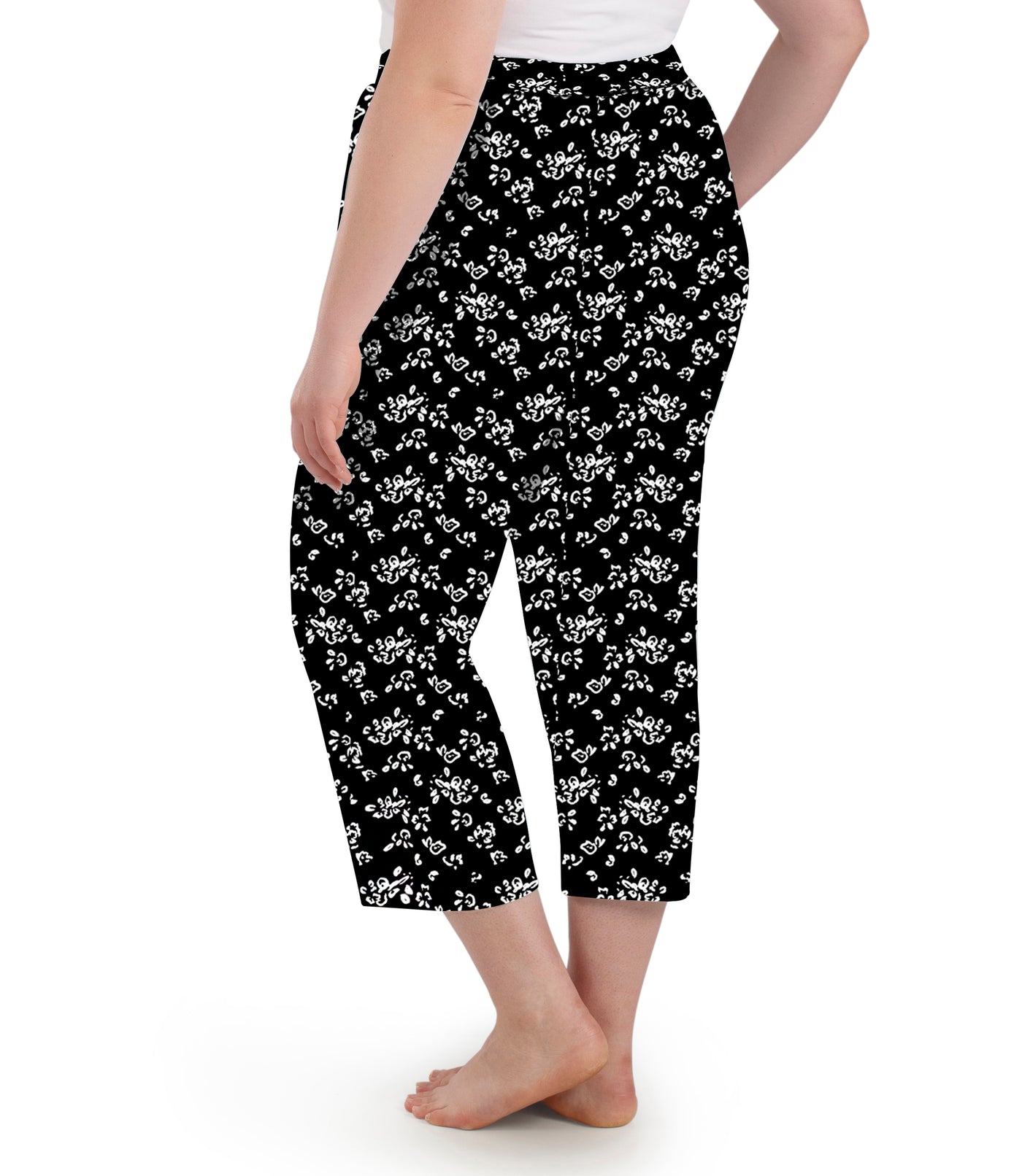 Plus size woman wearing JunoActive's JunoBliss pocketed sleep capris in fresh gardenia print facing back. 