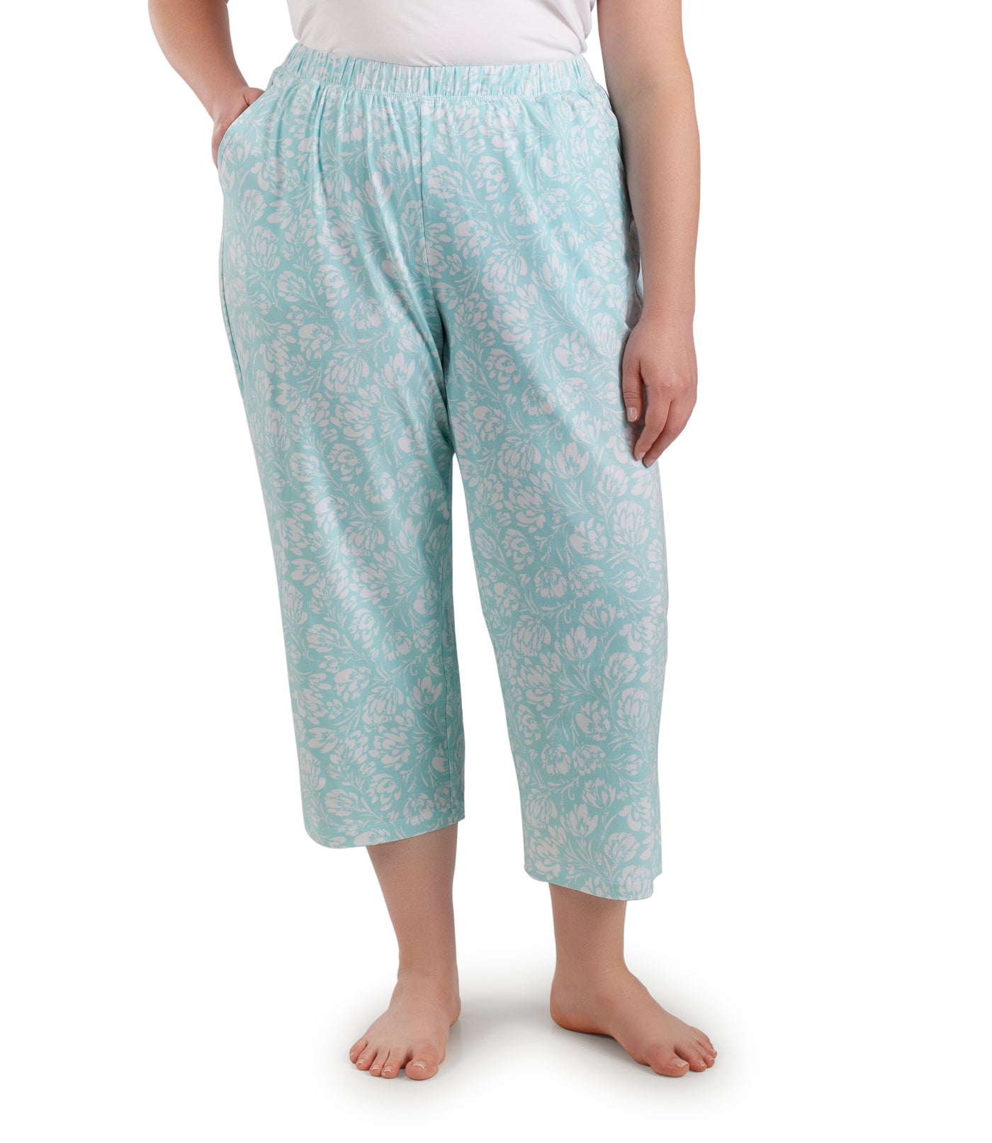 Bottom half of plus sized woman, facing front, wearing JunoActive JunoBliss Pocketed Sleep Capris Spring Blue Floral Print. The capri hemline is a few inches above ankle and a little longer than mid calf. Pockets on both sides.