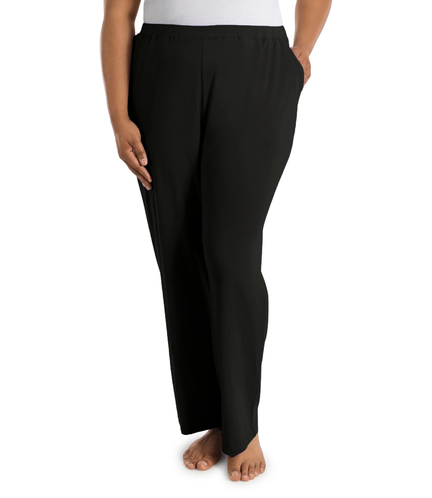 Plus size woman, facing front, wearing JunoActive’s JunoBliss Pocketed Sleep pant in color black. One hand in pocket and other by her side. 