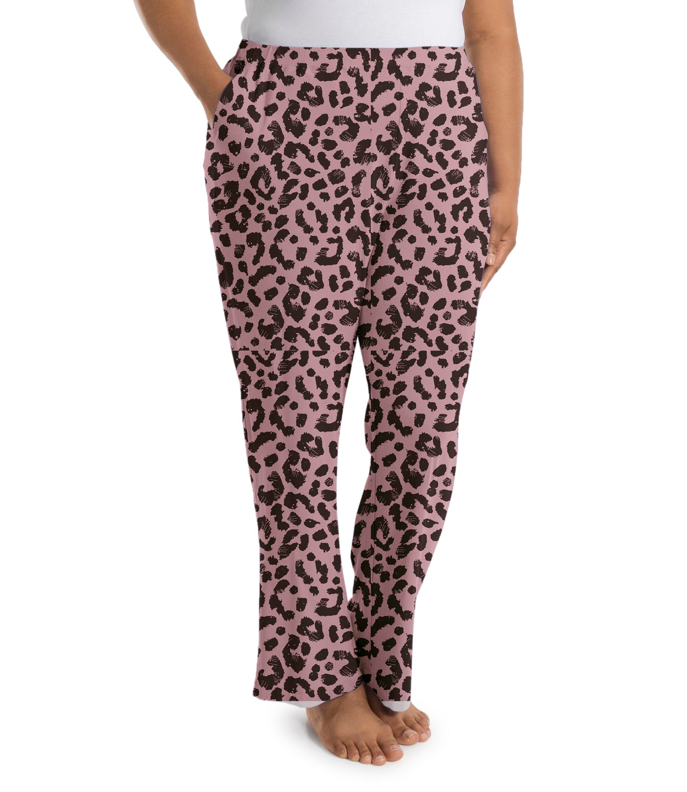 Plus size woman, facing side, wearing JunoActive’s JunoBliss Pocketed Sleep pant in color jungle rose print. One hand in pocket and other by her side.