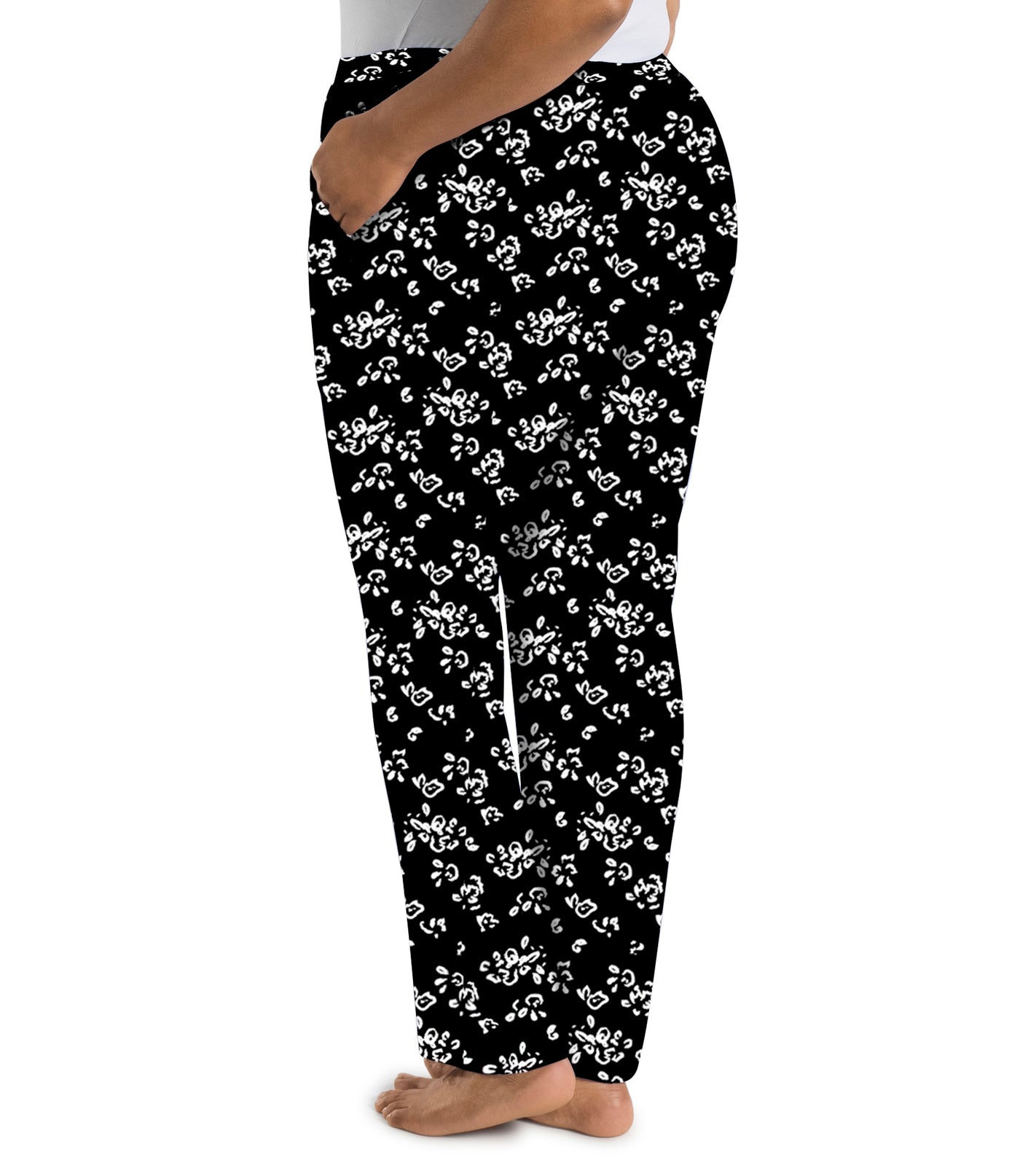 Plus size woman wearing JunoActive's JunoBliss pocketed sleep pants in fresh gardenia print in colors white and black. Model is facing back. 