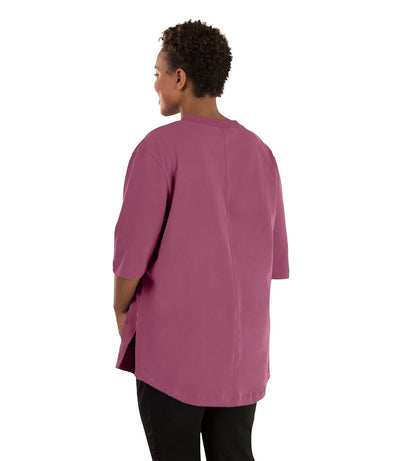 Plus size woman, facing back left, wearing JunoActive plus size Legacy Cotton Casual Tunic in the color Dusty Rose. She is wearing JunoActive Plus Size Leggings in the color black. 