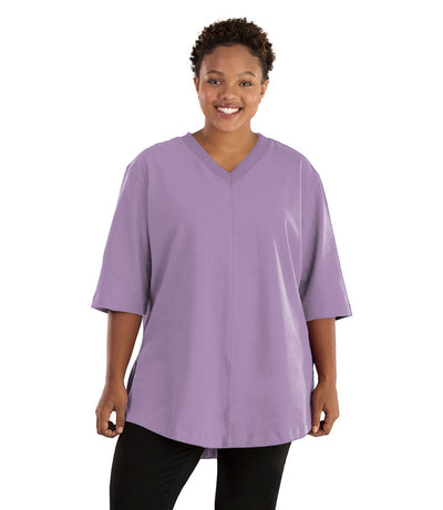 Plus size woman, facing front, wearing JunoActive plus size Legacy Cotton Casual Tunic in the color Lavender. She is wearing JunoActive Plus Size Leggings in the color black.