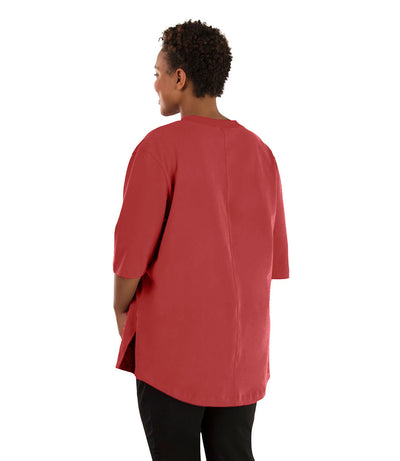 Plus size woman, facing back, wearing JunoActive plus size Legacy Cotton Casual Tunic in the color Sedona Red. She is wearing JunoActive Plus Size Leggings in the color black.