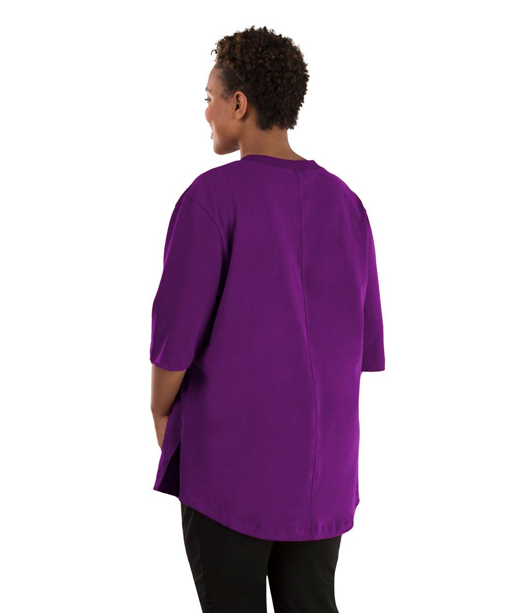 Plus size woman, facing back left, wearing JunoActive plus size Legacy Cotton Casual Tunic in the color  Heliotrope Purple. She is wearing JunoActive Plus Size Leggings in the color black