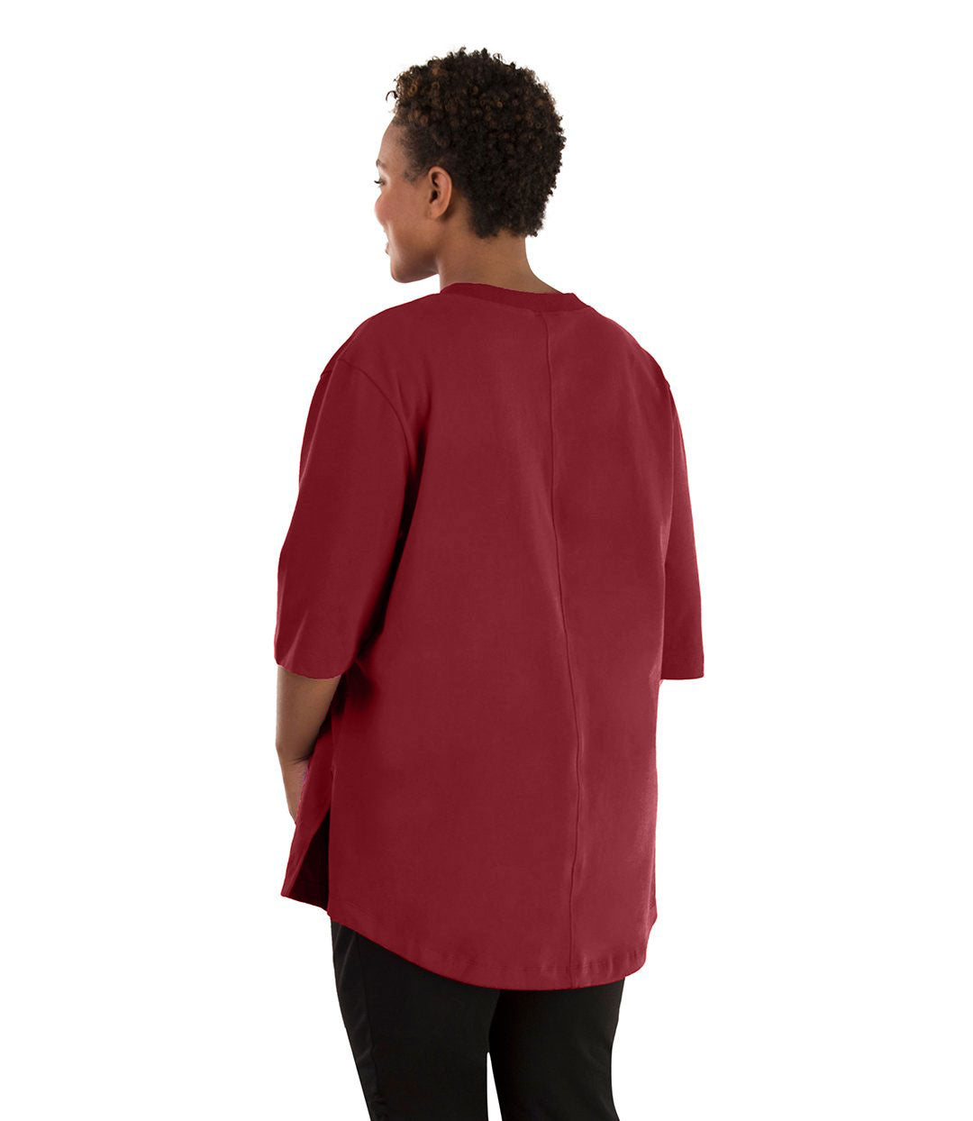 Plus size woman, facing back left, wearing JunoActive plus size Legacy Cotton Casual Tunic in the color Garnet. She is wearing JunoActive Plus Size Leggings in the color black. 