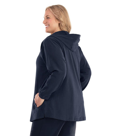 Plus size woman, facing back left, wearing JunoActive plus size Legacy Cotton Casual Button Up Hoodie in the color Navy Blue. She is wearing JunoActive Plus Size Leggings in the color Black.